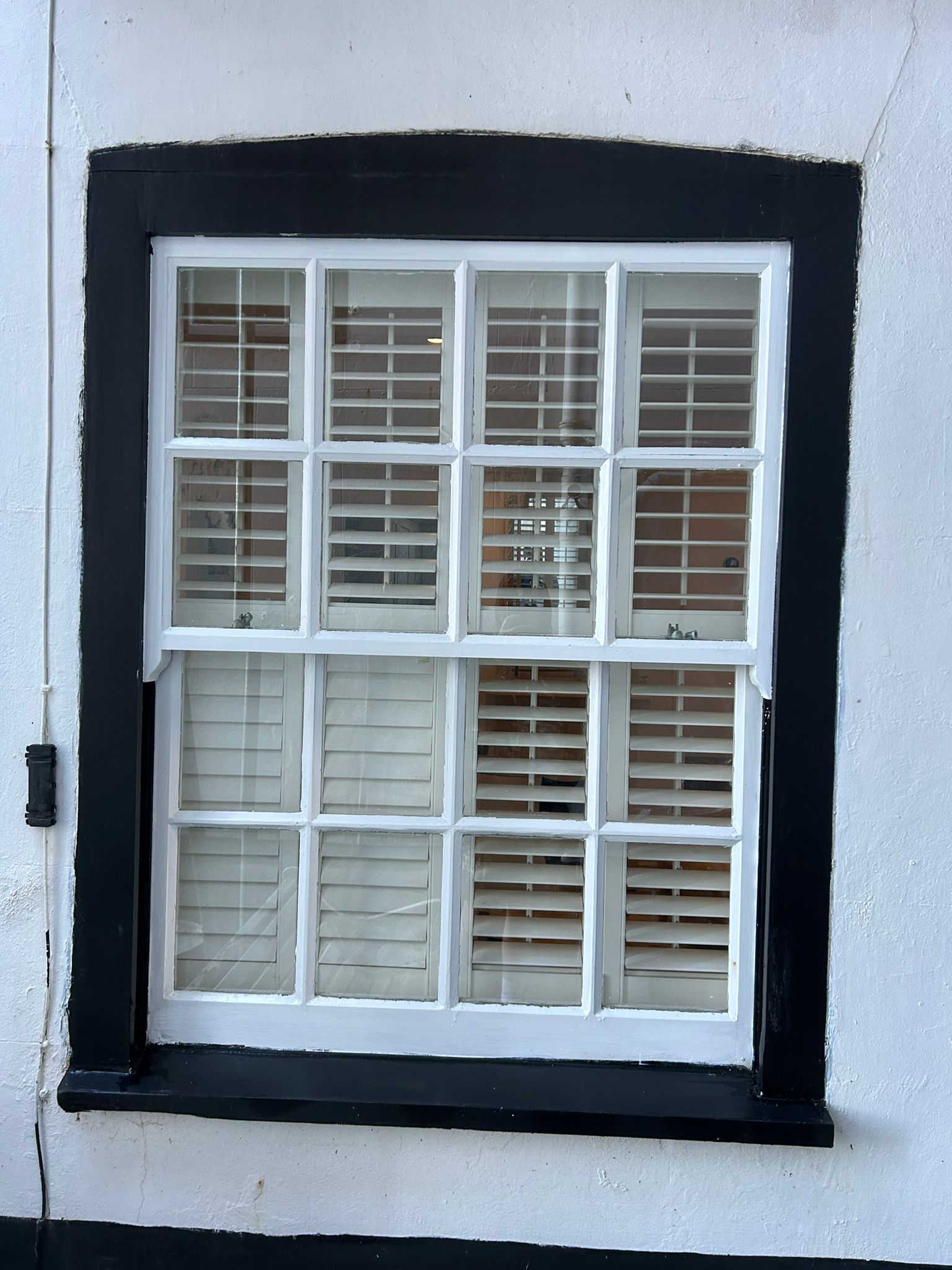 Black framed sash window with shutters