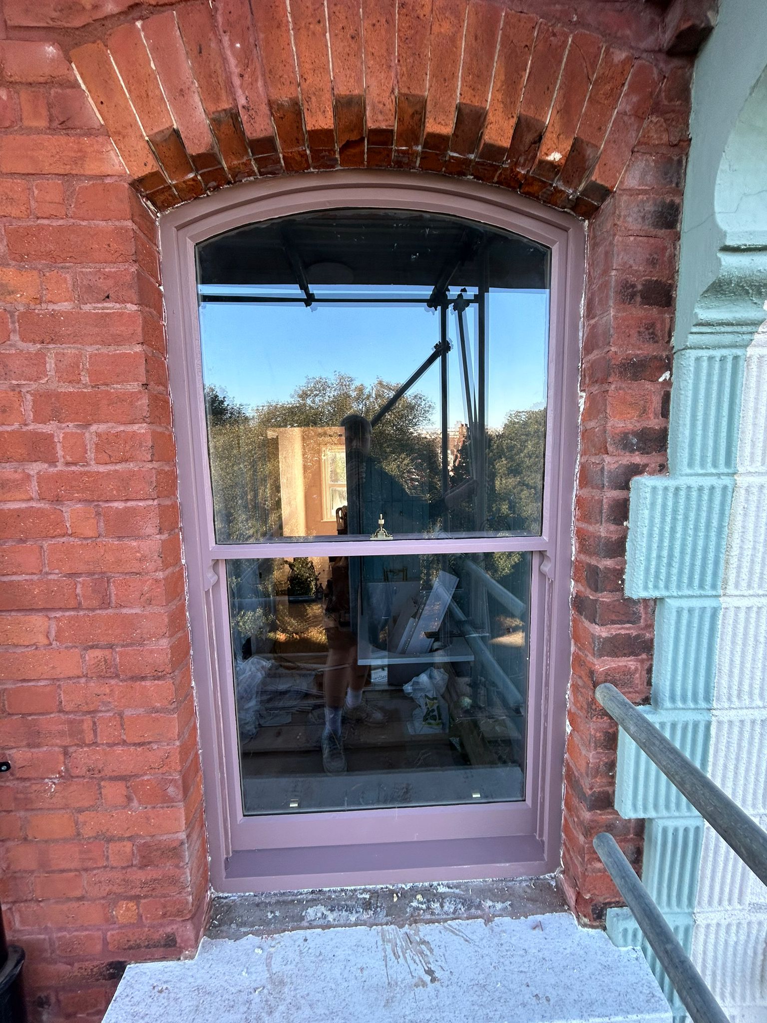 Arched sash window in brick, lilac painted